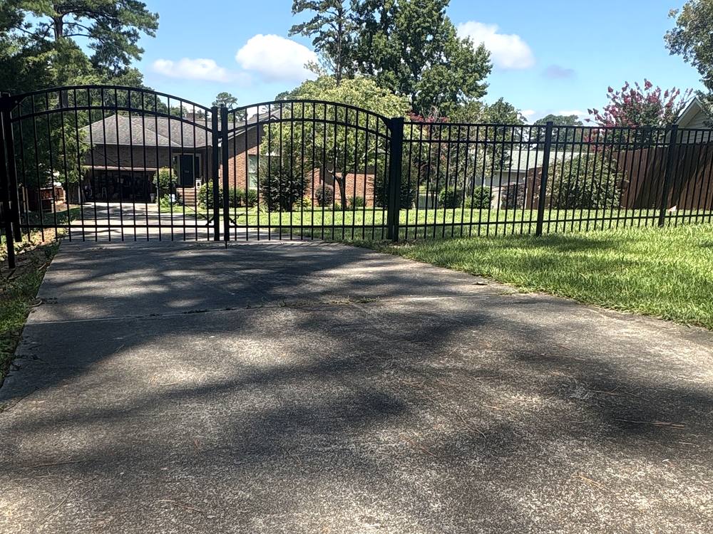 Black aluminum arched top double drive gate at the end of a driveway in the Midlands of South Carolina