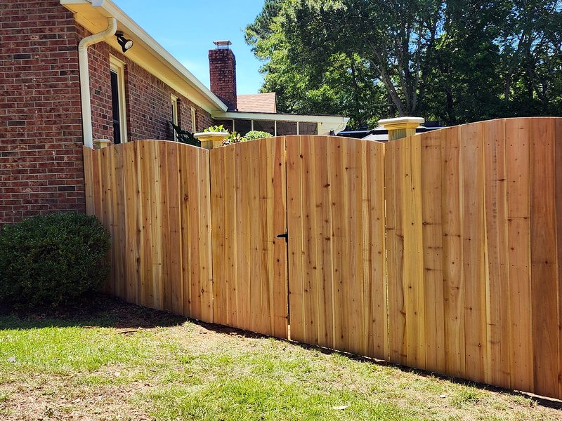 Cedar arch top privacy fence beside a brick home in Lexington, SC