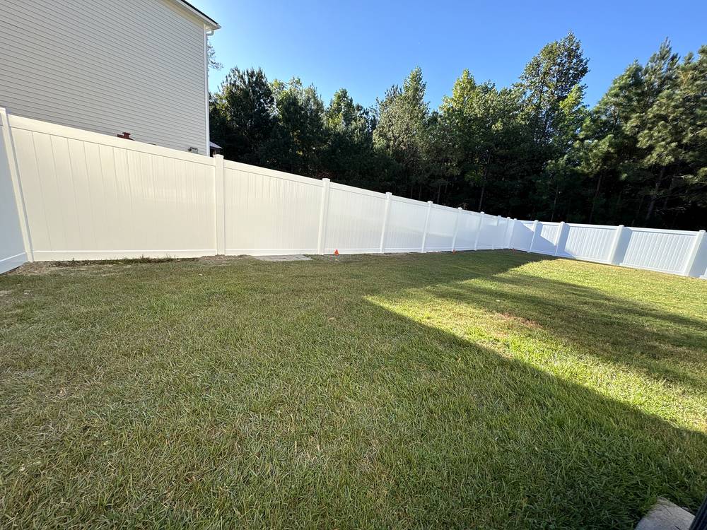 White vinyl privacy fence running along a green lawn in the Midlands of South Carolina