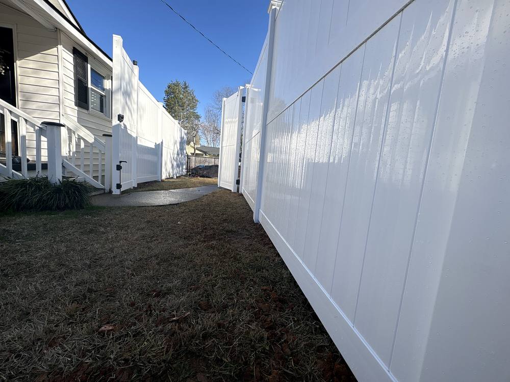 White vinyl privacy fence with a walk gate along a side yard in the Midlands of South Carolina