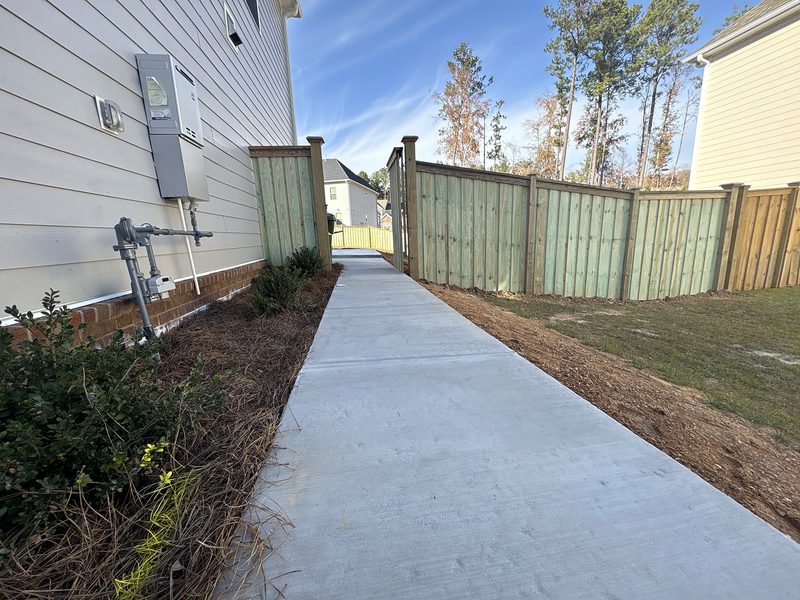 Wood cap and trim fence and gate beside a new concrete walkway in Irmo, SC