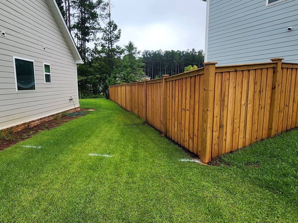 Wood cap and trim privacy fence along a green side yard in the Midlands of South Carolina
