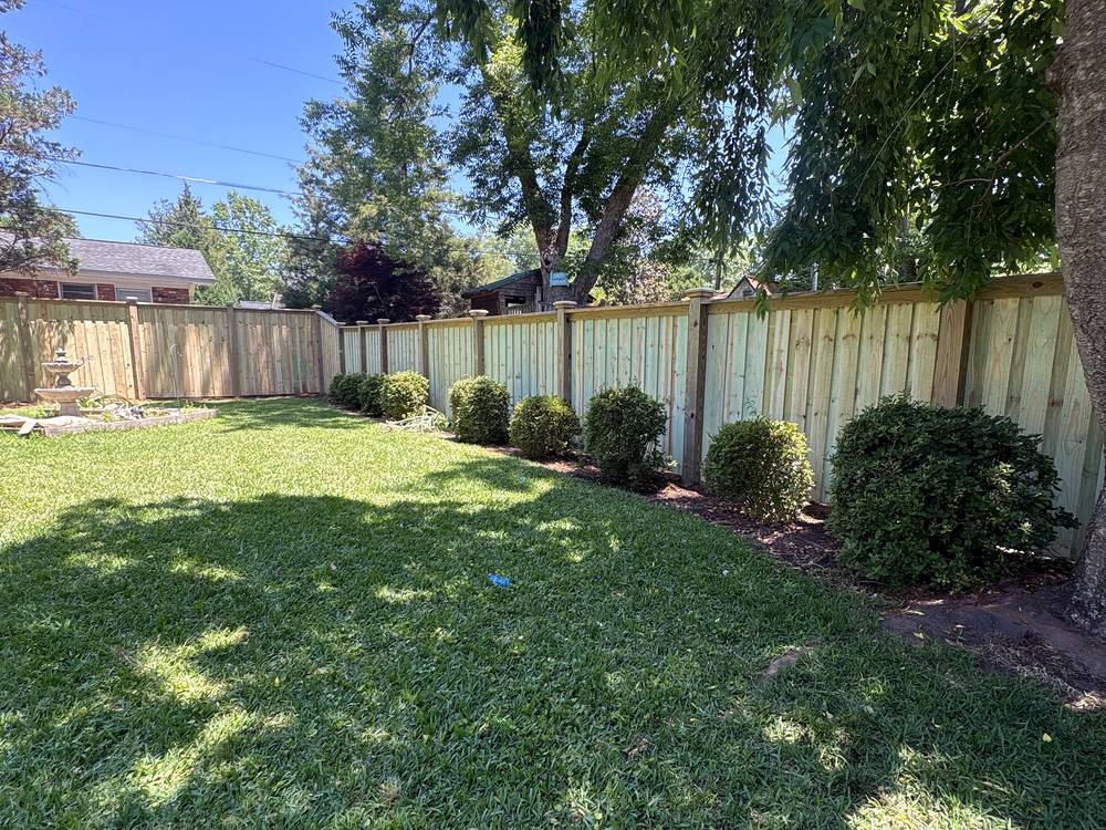 Wood cap and trim privacy fence behind a line of shrubs in a backyard in Irmo, SC
